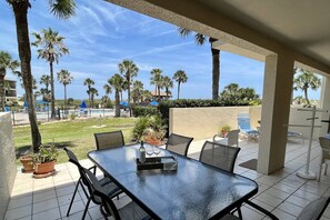 An outdoor patio with a glass table, chairs, and potted plants.