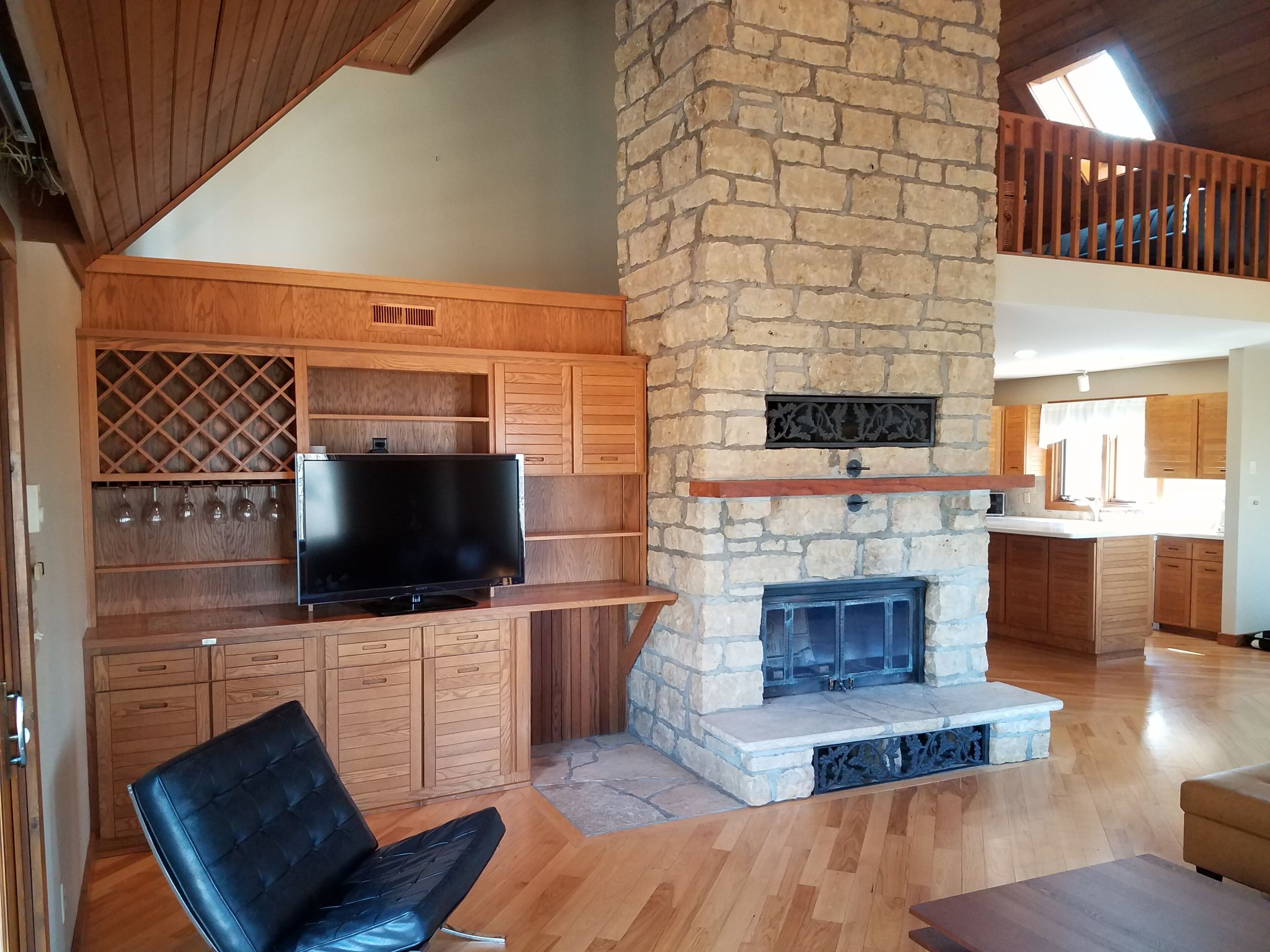 Living room with wine bar and stone fireplace.