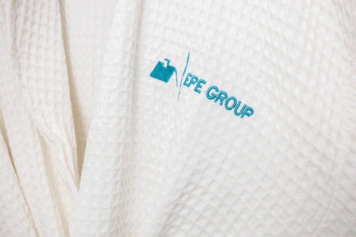 A white fabric with a logo and text, likely part of a garment.