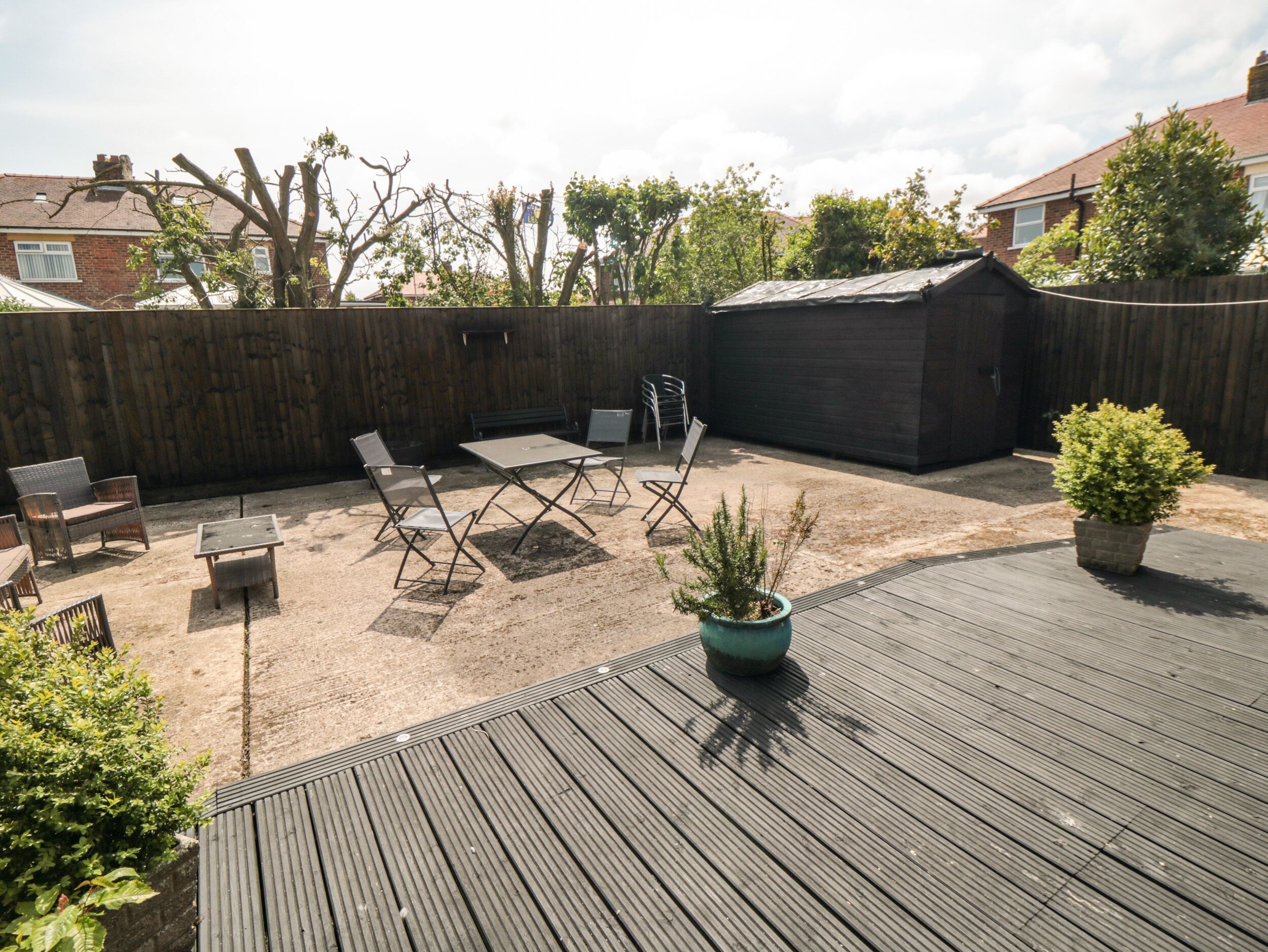 A wooden deck with outdoor furniture, a small garden, and a wooden fence.