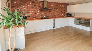 Una cocina moderna con protector mural de ladrillo, armarios blancos y encimera de madera.