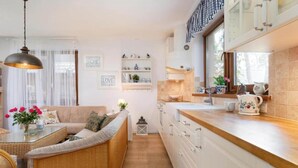 A modern kitchen with white cabinets, a wooden countertop, and a hanging light fixture.