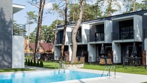 A modern hotel with a swimming pool, outdoor seating, and a well-maintained garden. - Comfortable holiday home with garden, summer pool (Pobierowo)