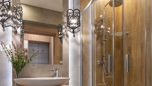 Un baño moderno con ducha envuelta en vidrio, un lavabo sobre encimera y un espejo sobre el lavabo.