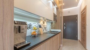 Una cocina moderna con cafetera espresso integrada, un lavamanos y un salpicadero decorativo.