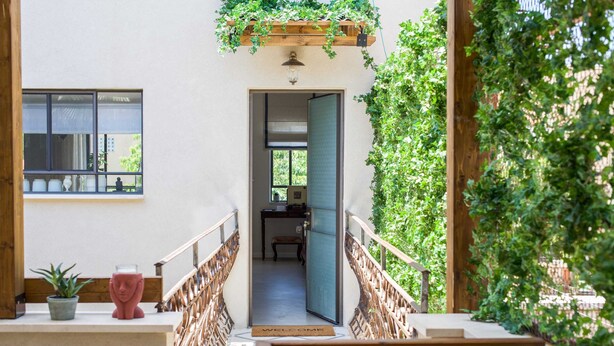 A wooden staircase leading to a room with a view of a garden. - Luxurious Urban Retreat with Private Outdoor Area (Tel Aviv-Yafo)