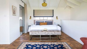 A bedroom with a bed, bedside tables, a hanging light fixture, a patterned bench, and a large window with curtains. - Luxurious Urban Retreat with Private Outdoor Area (Tel Aviv-Yafo)