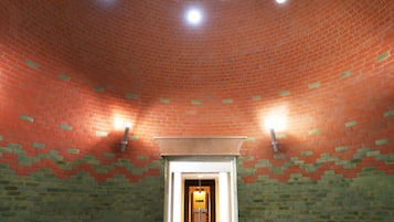An indoor swimming pool with a brick ceiling and a central light fixture.
