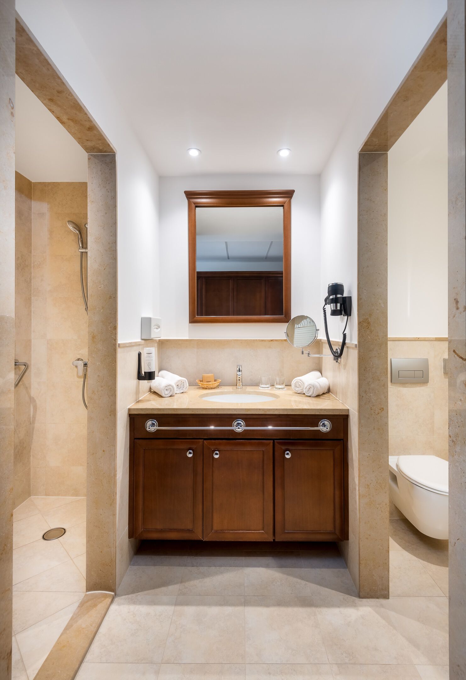Ein modernes Badezimmer mit Marmorwaschbecken, Holz-Waschtisch und einer begehbaren Dusche.