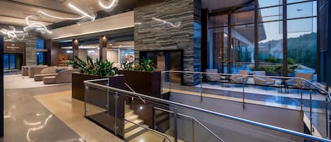 A modern lobby with a stone wall, seating areas, and a view of the outdoors.