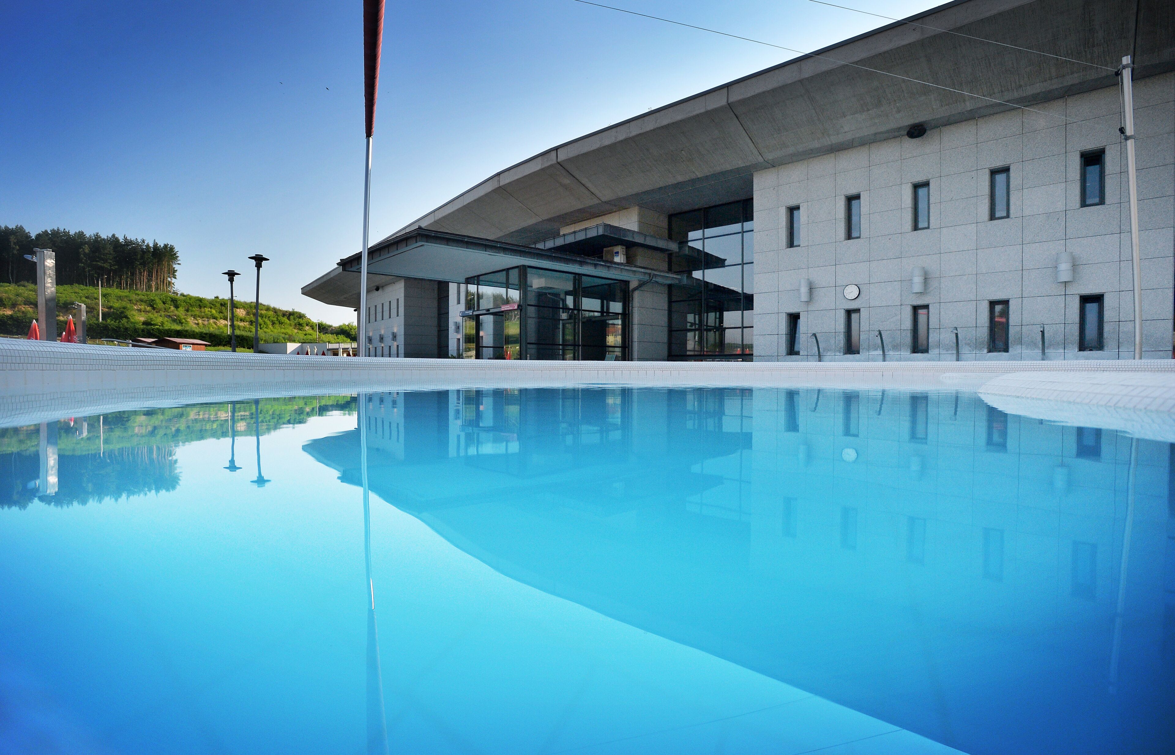 A modern building with a swimming pool in front.