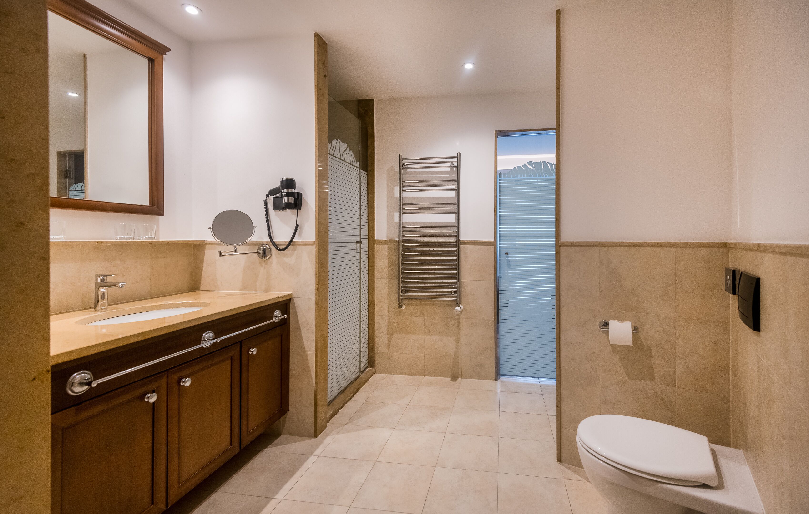 A modern bathroom with a large mirror, a sink, a toilet, and a shower area.
