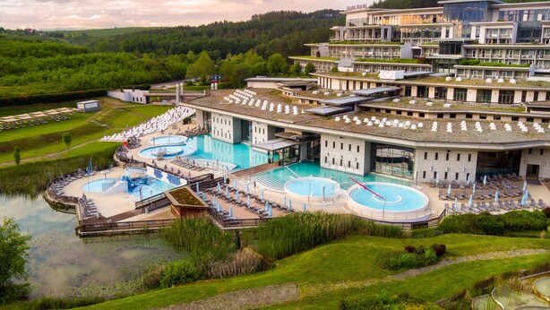Un complexe hôtelier doté de plusieurs piscines, d’un grand bâtiment à toit plat et entouré d’un paysage naturel.