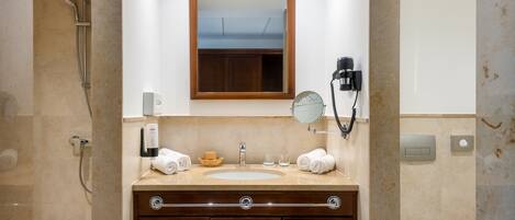 Un baño con tocador de madera, espejo, toallero, secador de pelo y retrete.