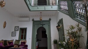 A spacious interior with a high ceiling, a balcony with a wrought iron railing, and a variety of potted plants. - Private Riad for 4 people In Historic Neighborhood/ 5 minutes to Jemaa El-Fna 

 (Marrakesh)