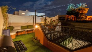 A rooftop terrace with a seating area, a grill, and a view of the city skyline at dusk. - Private Riad for 4 people In Historic Neighborhood/ 5 minutes to Jemaa El-Fna 

 (Marrakesh)