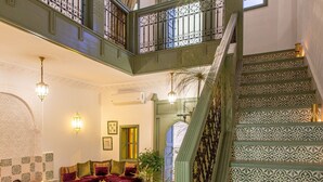 A spacious lobby with a staircase, a seating area, and a potted plant. - Private Riad for 4 people In Historic Neighborhood/ 5 minutes to Jemaa El-Fna 

 (Marrakesh)