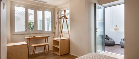 Une chambre moderne avec une grande fenêtre, un bureau en bois, un banc et un lit.