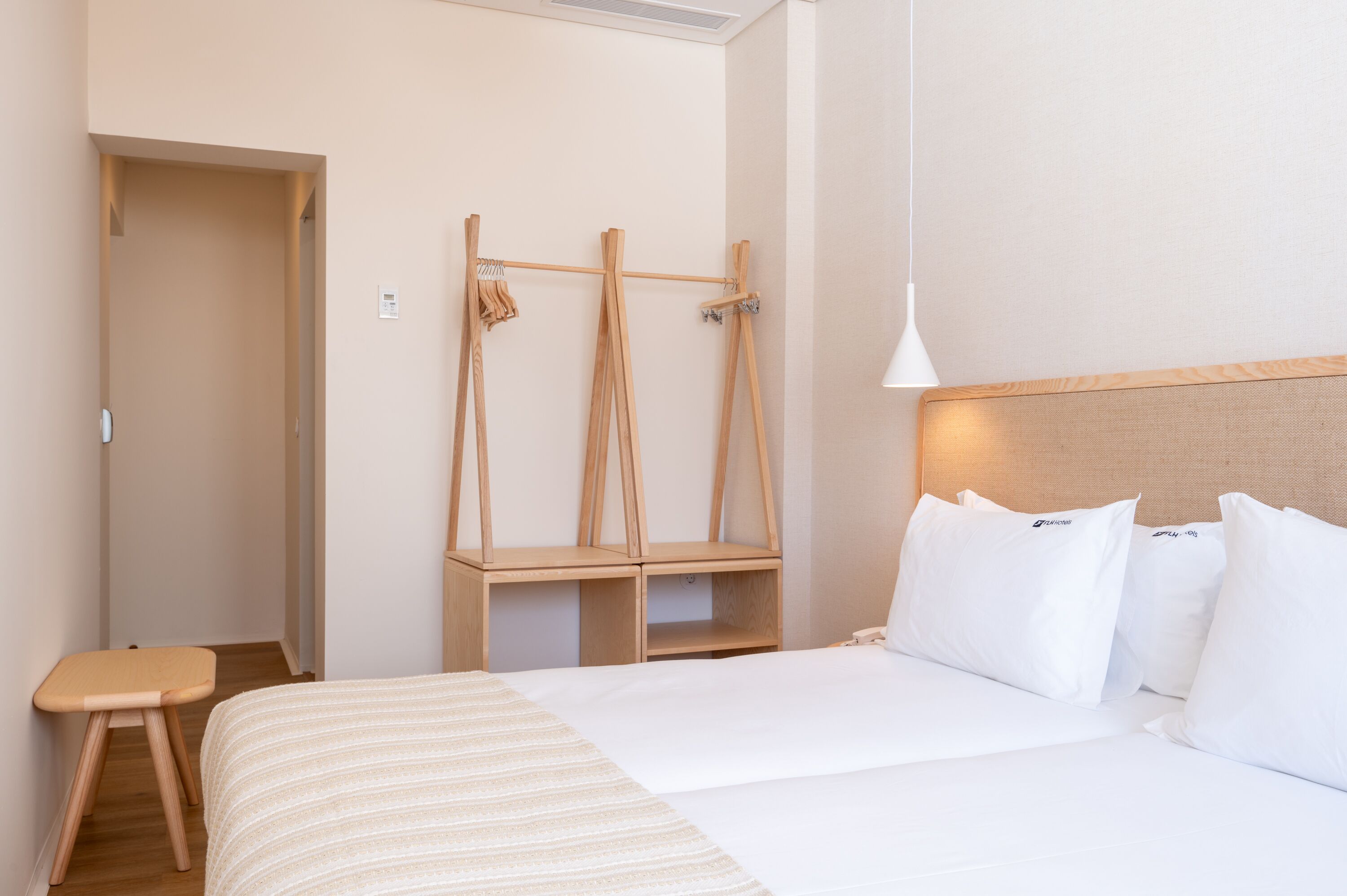 Ein Hotelzimmer mit einem Bett, einer Holzbank und einem Kleiderhaken.
