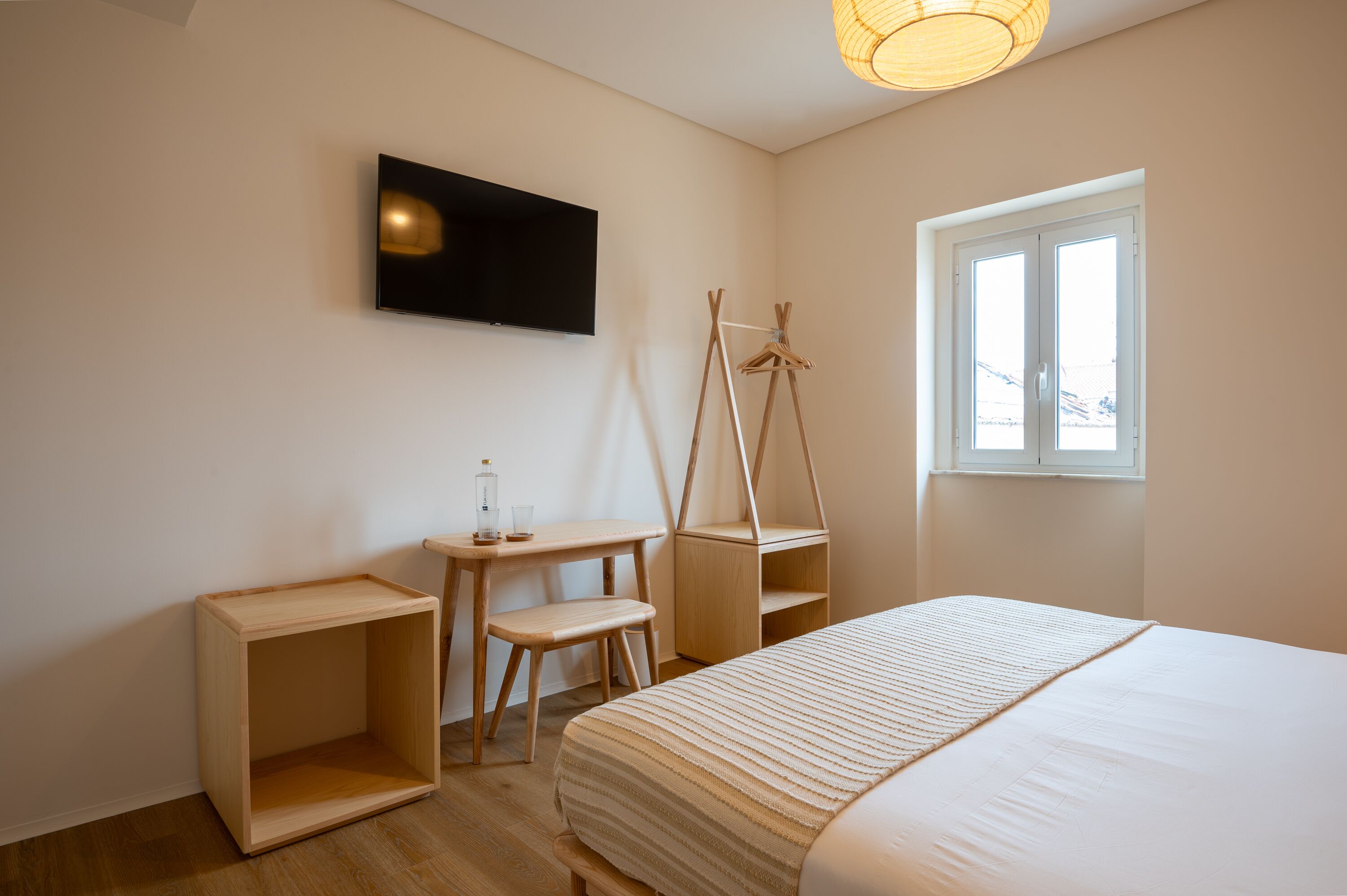 Un dormitorio con una cama, un escritorio, una silla, un televisor y una ventana.