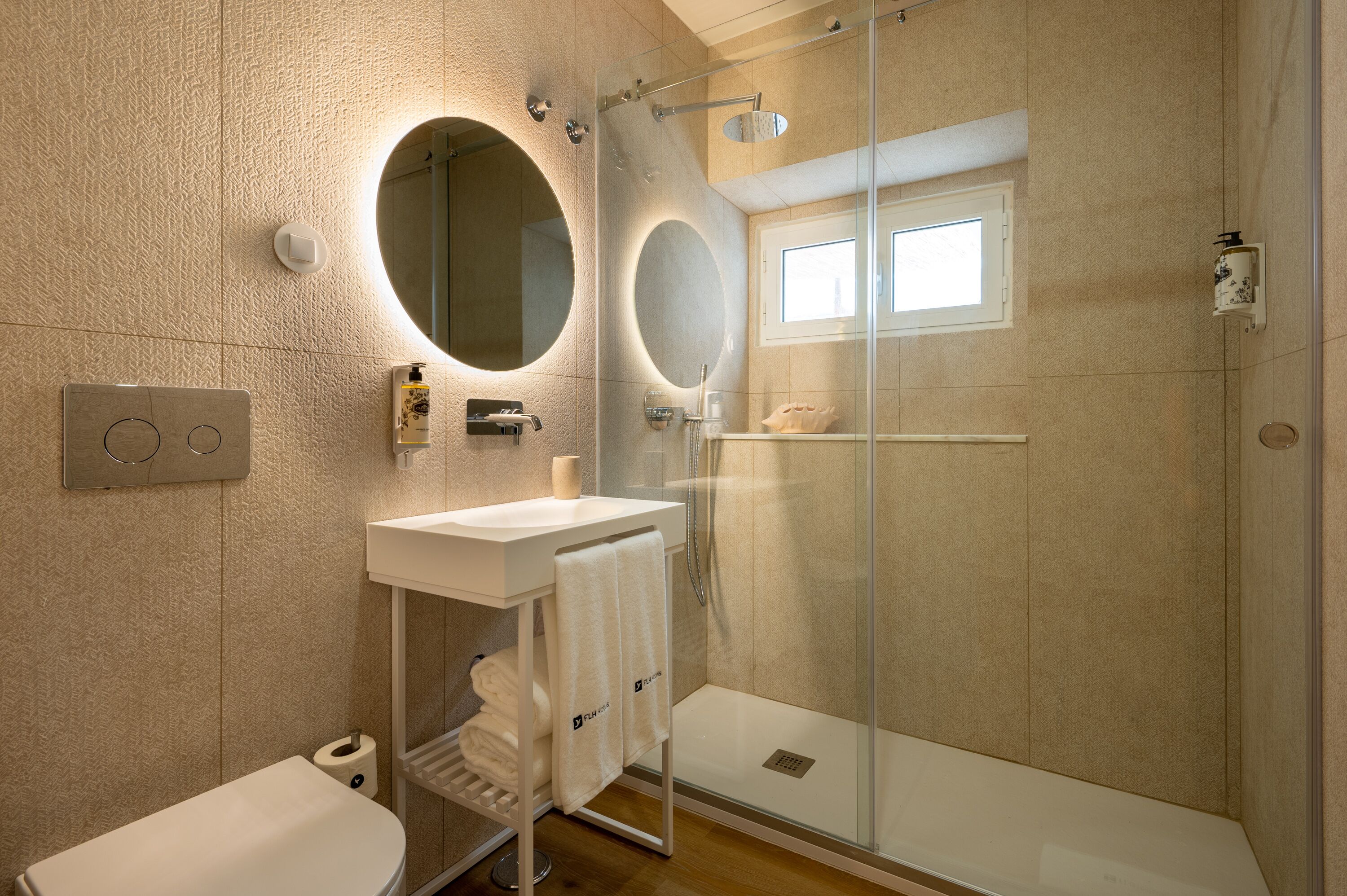 A modern bathroom with a glass-enclosed shower, a white sink, and two large mirrors.