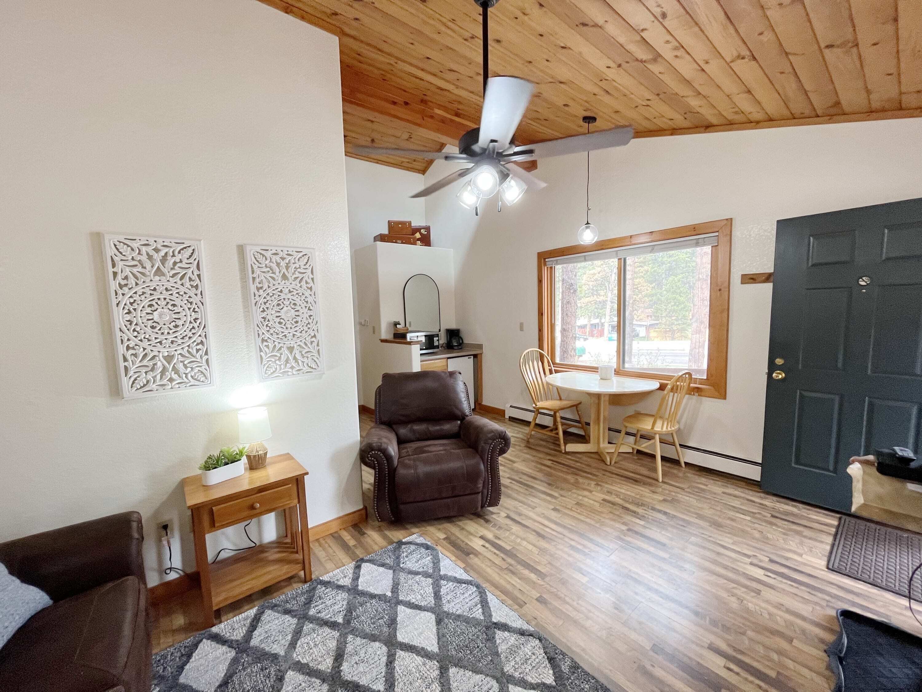 A cozy living room with a brown leather sofa, a wooden coffee table, and a ceiling fan.