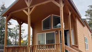 A wooden cabin with a covered porch and a small staircase leading to the entrance. - Tiny home Within Campground (Woodland Park)