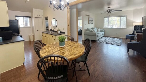 A spacious living area with a dining table, chairs, a sofa, and a ceiling fan.