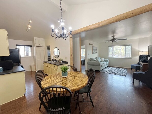 A spacious living area with a dining table, chairs, a sofa, and a ceiling fan.