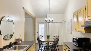 A kitchen with a dining table, chairs, a sink, cabinets, a stove, and a chandelier.
