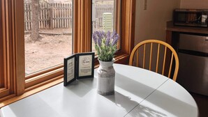 A round table with a white tablecloth, a vase with lavender flowers, and a framed sign. - Cabin Suite Bed & Breakfast (Woodland Park)