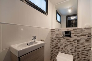 A modern bathroom with a white sink, a mirror, and a patterned wall. - Parque Santiago II 87 - Two Bed (Playa de la Américas)