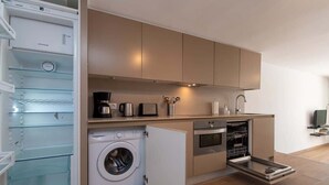 A compact kitchen with a built-in washing machine, a dishwasher, and a coffee maker. - Parque Santiago II 87 - Two Bed (Playa de la Américas)