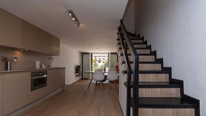 A modern kitchen with a wooden staircase leading to a dining area. - Parque Santiago II 87 - Two Bed (Playa de la Américas)