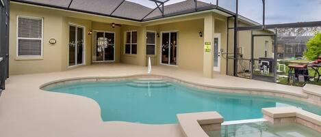 A pool area with a glass enclosure, beige walls, and a small hot tub.