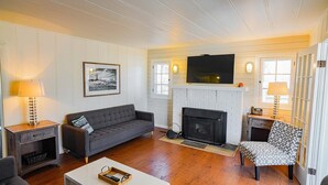 Una sala de estar con chimenea, un sofá, un sillón y un televisor.