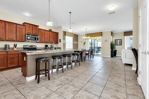 A spacious kitchen with wooden cabinets, a central island with bar stools, and a large window providing natural light.