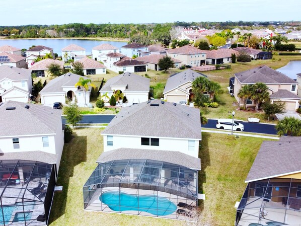 A residential area with houses, a swimming pool, and a lake in the background.