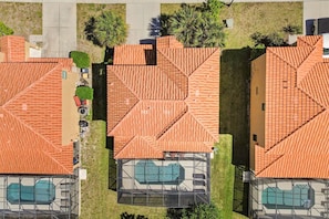 A residential area with multiple houses, each with a tiled roof and a swimming pool.