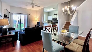Ein modernes Wohnzimmer mit einem Glastisch, einer Couch und einem Deckenventilator.
