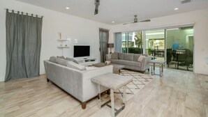 A modern living room with a sofa, a coffee table, and a flat-screen TV. - Private Pool | 15 Min to Disney | Gated Resort 1472 (Kissimmee)