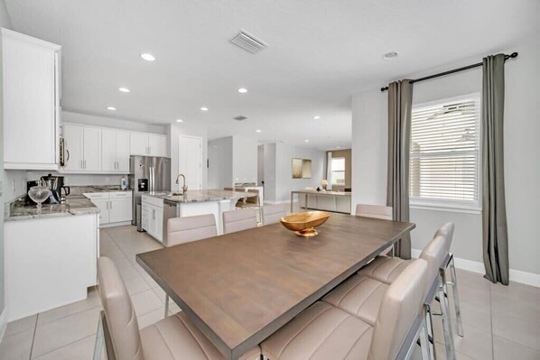 A modern kitchen with white cabinets, stainless steel appliances, and a central island with seating. - Beautiful Private Pool & Spa | Near Disney 7673 (Kissimmee)
