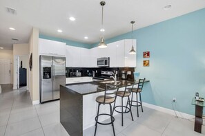 A modern kitchen with a central island, stainless steel appliances, and bar stools.