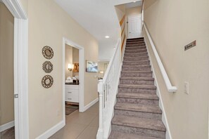 Staircase leads to a spacious upper floor with decorative wall art and a no-smoking policy.