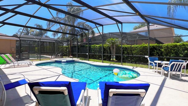 Ein überdachter Pool mit Liegestühlen und Blick auf Palmen.