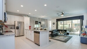 Una cocina moderna con armarios blancos, electrodomésticos de acero inoxidable y una isla central.