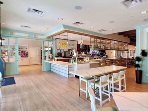 A modern cafe with a central island, bar area, and seating.