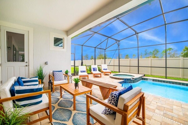 A sunroom with a pool, seating area, and a view of the backyard. - Star Wars Game Room • Mickey & Harry Potter • Pool & Spa • Gated Near Disney (Kissimmee)