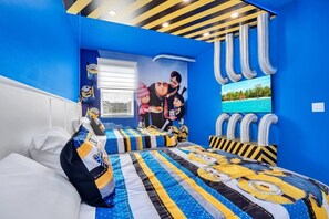 A bedroom with two beds, blue walls, and a mural of Minions.
