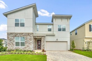A modern two-story house with a stone facade, a garage, and a well-maintained lawn.